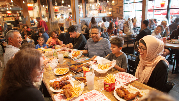 Customers sharing Albaik BBQ Baik food in a modern, friendly restaurant.