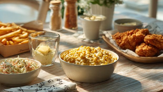 Albaik sides menu spread with coleslaw, corn, fries, and garlic sauce, styled for both KSA and USA readers